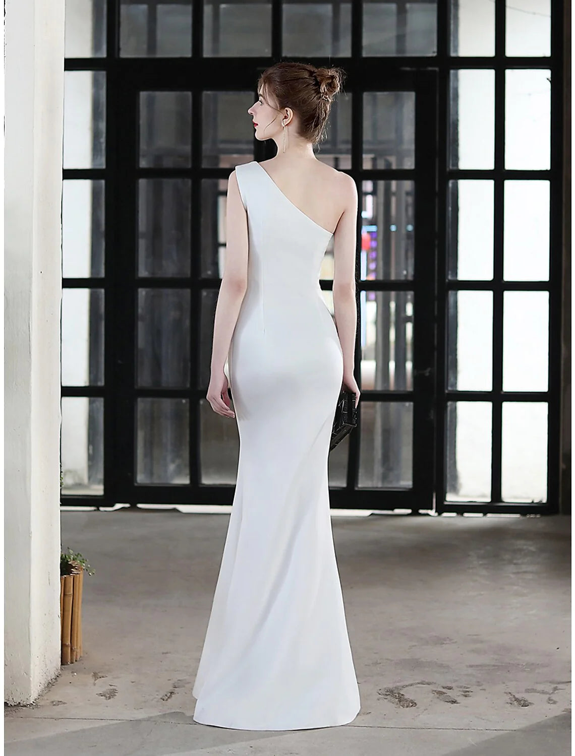 Back view of a woman in a floor-length one-shoulder satin gown.