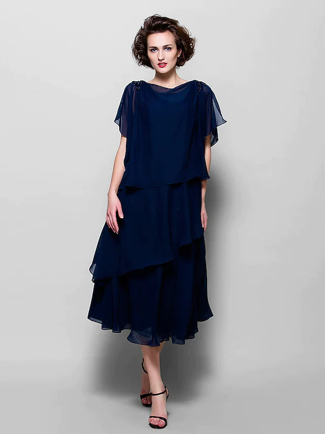 Model wearing an elegant plus size A-line mother of the bride dress with a cowl neck, short sleeves, and ruffles.