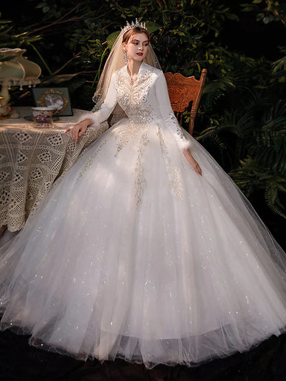 Front view of a bride wearing an elegant princess ball gown wedding dress with V-neck and long lace sleeves.