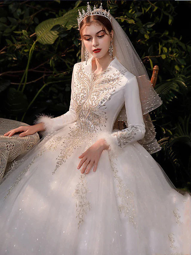 Close-up of the V-neckline and intricate lace details on the long sleeves of the wedding dress.