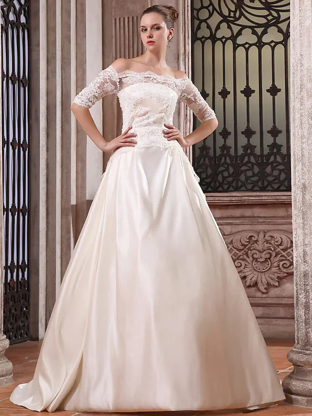 Bride in a white scalloped off-shoulder ball gown wedding dress with half sleeves and a court train.