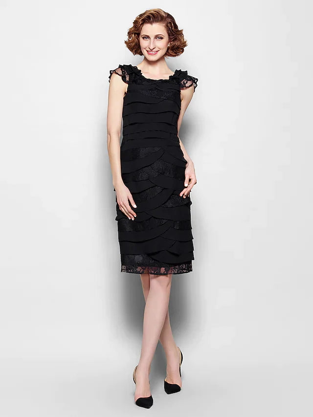 Woman wearing a black scoop neck knee-length Mother of the Bride dress with lace and pleats.
