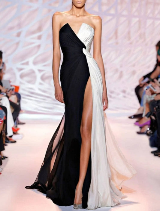 Model wearing a white strapless sheath column formal dress with a slit and sweep train, front view.