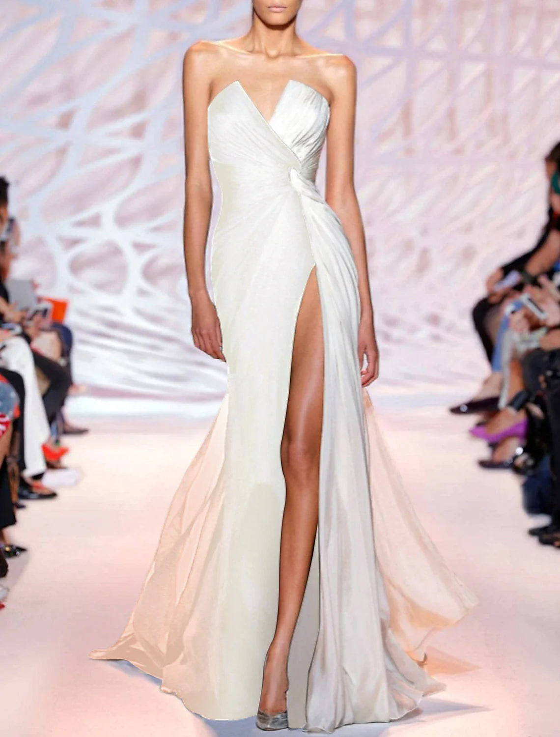 Model wearing a white strapless sheath column formal dress with a slit and sweep train, back view.