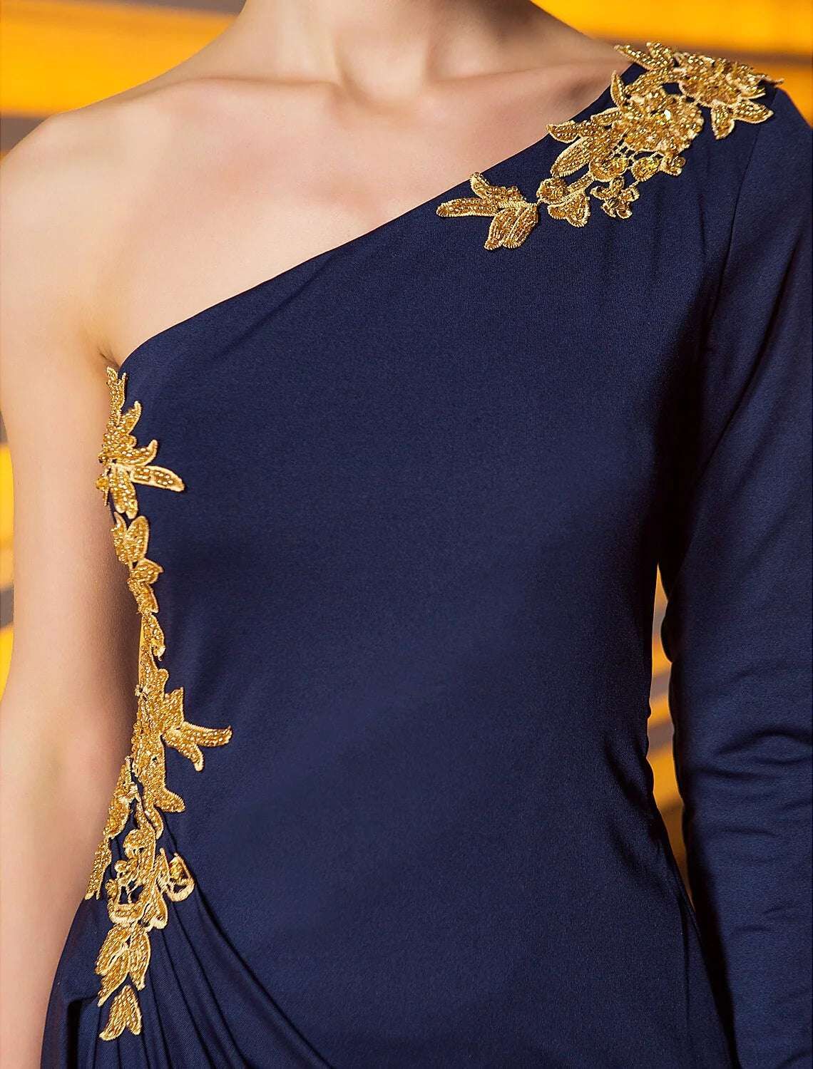 Close-up of the intricate beading and appliques on the one-shoulder evening dress.