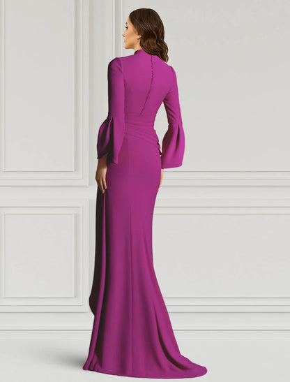 Side view of a woman in a black sheath evening gown, highlighting the long sleeves and floor-length design.