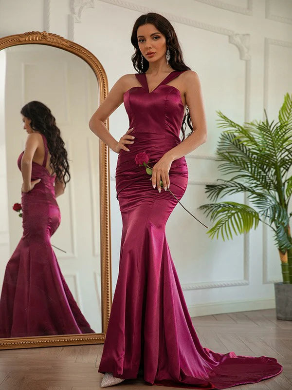 Woman wearing a long silk-like satin ruched halter prom dress, front view.
