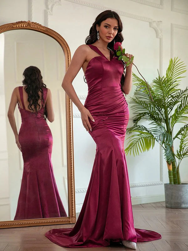 Back view of a woman in a long silk-like satin ruched halter prom dress.