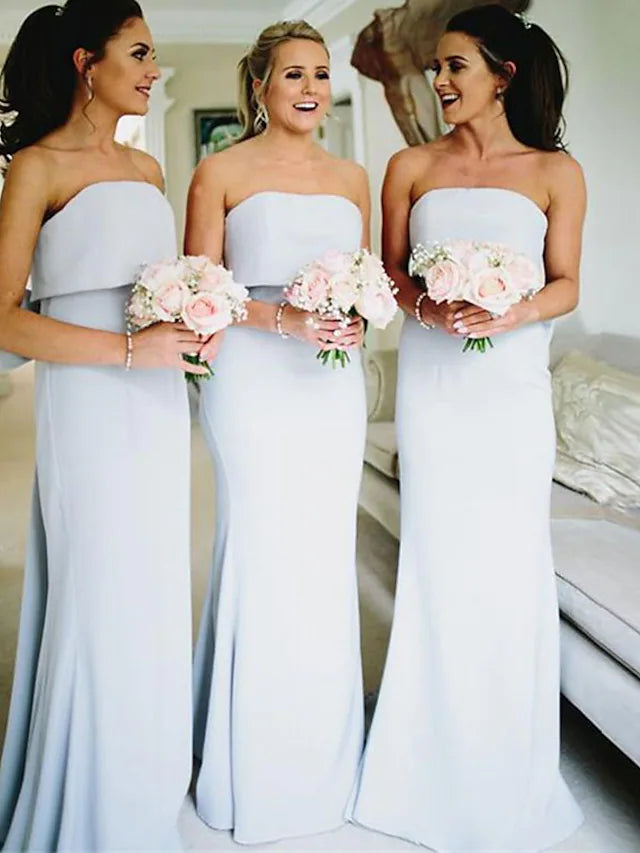 Woman wearing an elegant light blue strapless jersey bridesmaid dress with ruffles and bows.