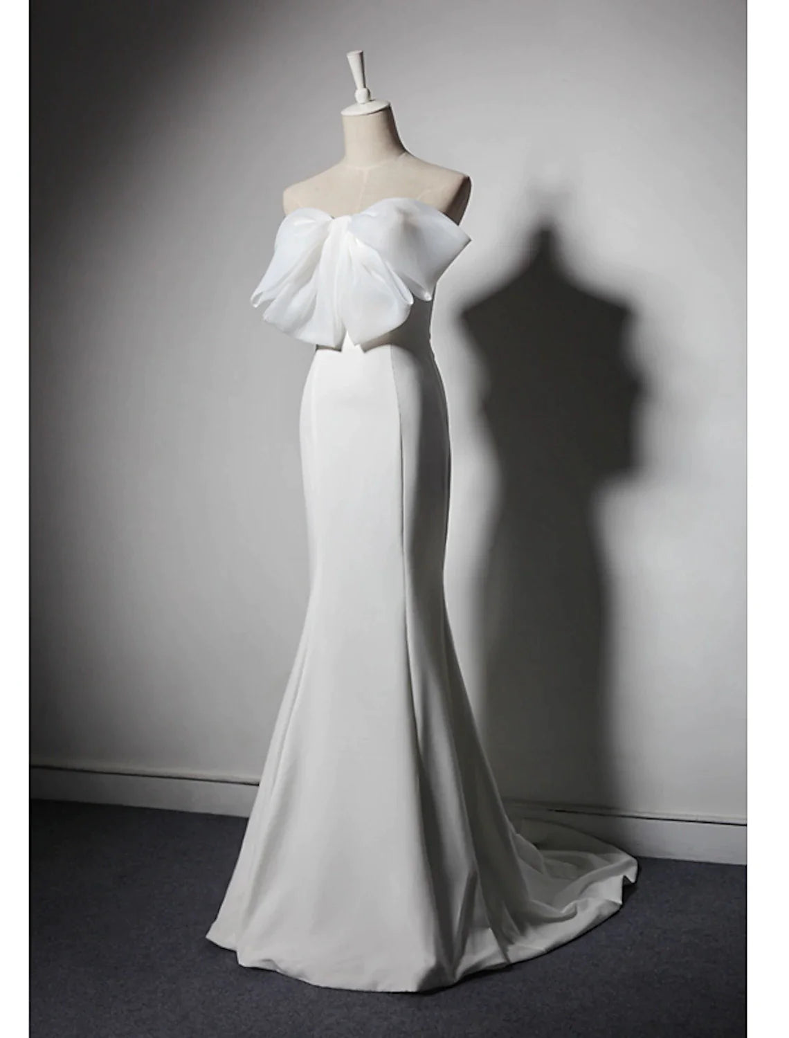 Woman posing in a strapless mermaid trumpet evening gown, showcasing the stretch fabric and train.