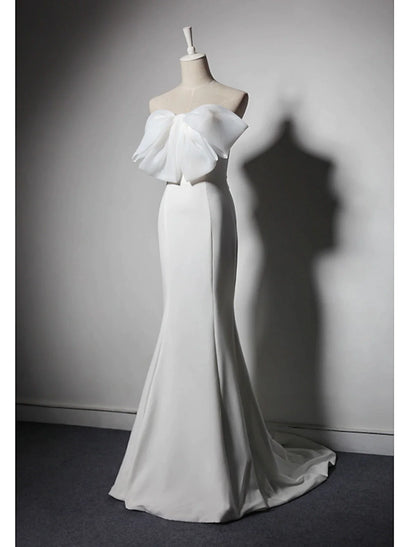 Woman posing in a strapless mermaid trumpet evening gown, showcasing the stretch fabric and train.