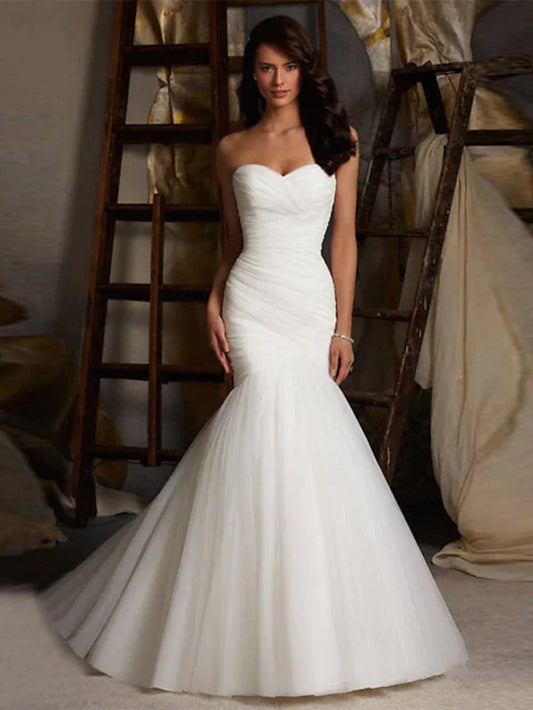 Front view of a model wearing a white strapless sweetheart tulle wedding dress with ruched bodice and court train.