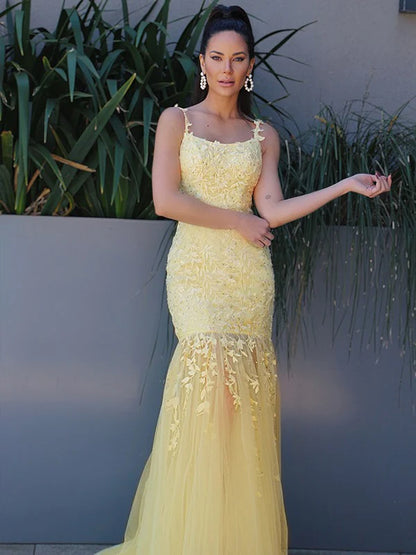 Elegant yellow tulle prom dress with spaghetti straps and applique detailing.