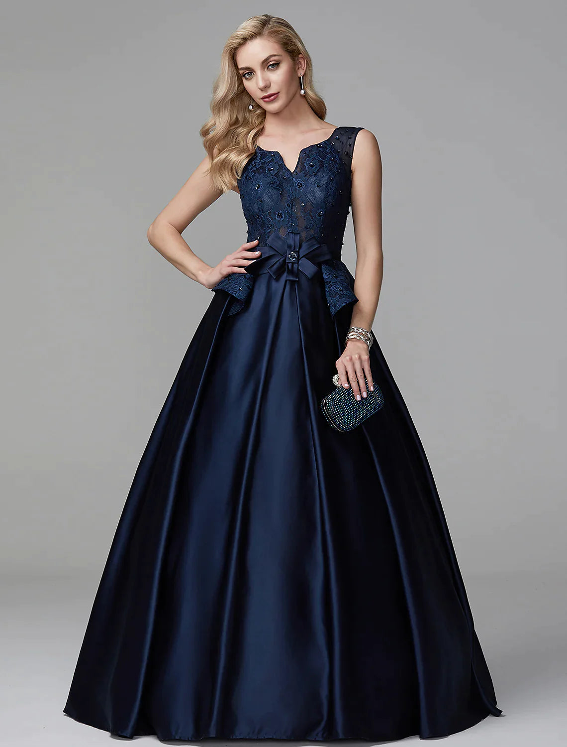 Model wearing an elegant V-neck ball gown with lace and peplum detail.