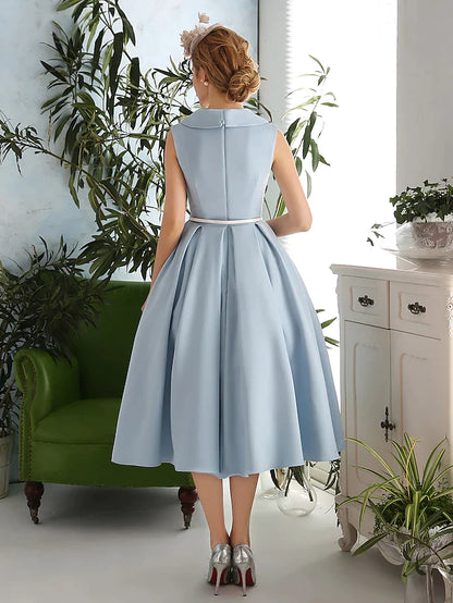 Woman posing in a vintage-inspired cocktail dress with a V-neck.
