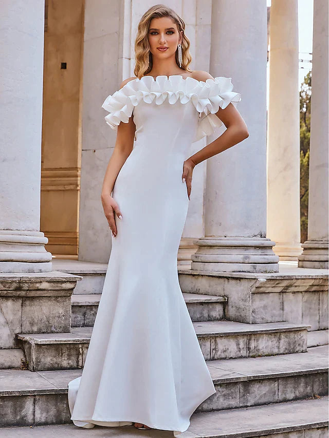 Model wearing a white off-shoulder ruffled mermaid wedding dress, front view.
