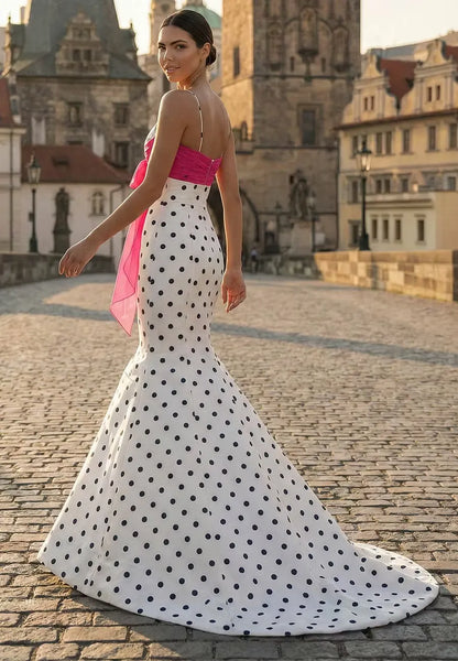 Side view of a model wearing the white polka dot mermaid prom dress with a V-neckline.