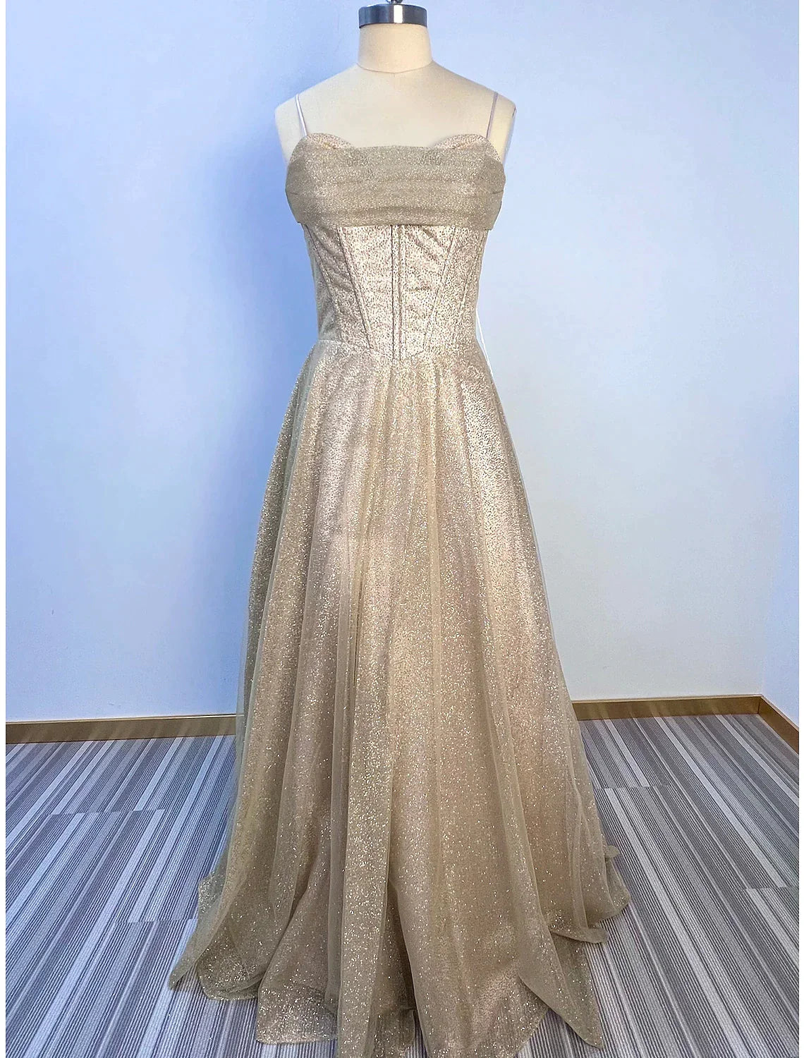 Close-up of the elegant cowl neck and corset bodice on a glitter tulle dress.