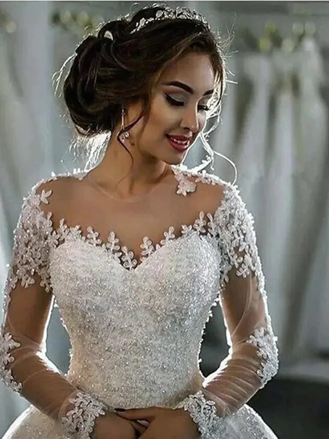 Close-up of intricate lace detail on the long illusion sleeve of the wedding dress.