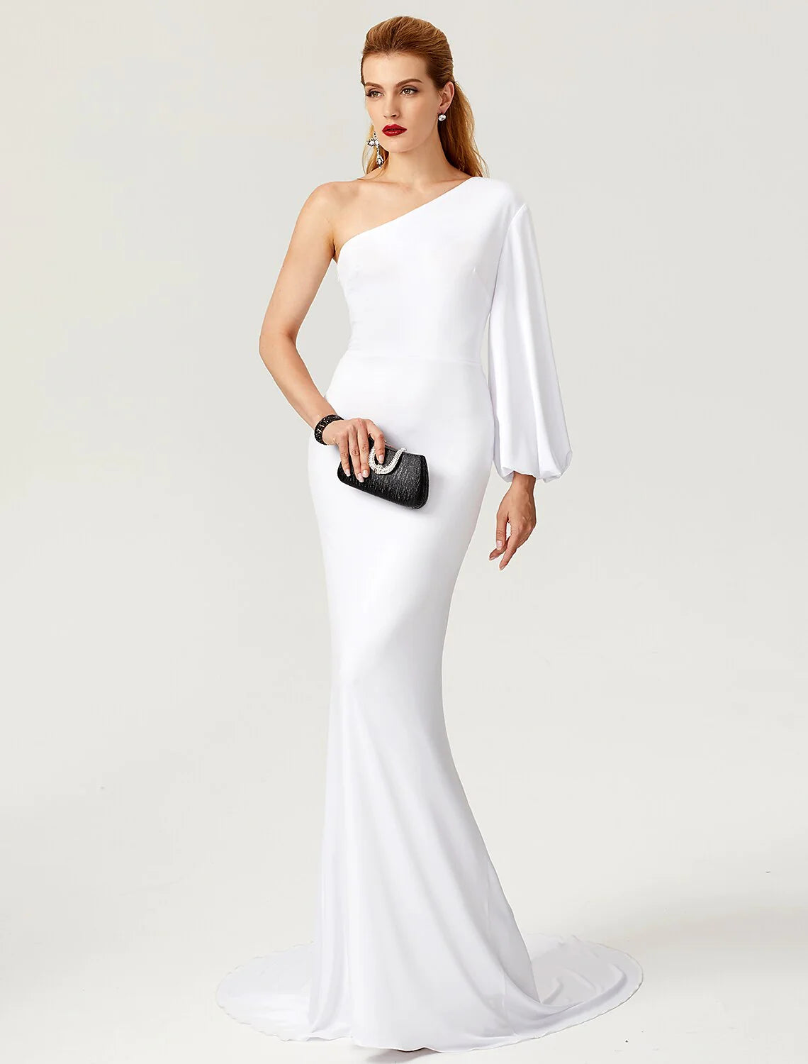 Full-length view of a woman in a dark one-shoulder long sleeve formal gown.