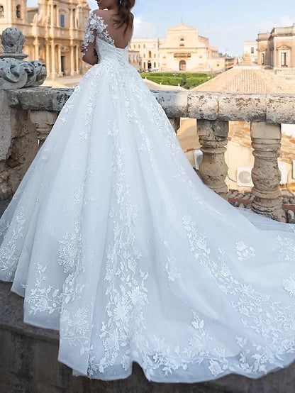 Side profile of the bride in the sparkling ball gown wedding dress with a flowing chapel train.