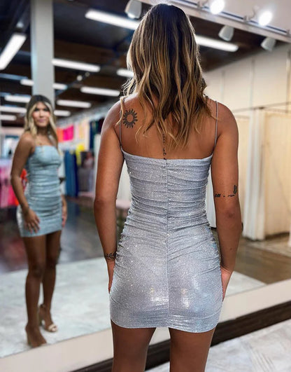 Side view of a woman in a sparkly silver bodycon short homecoming dress.