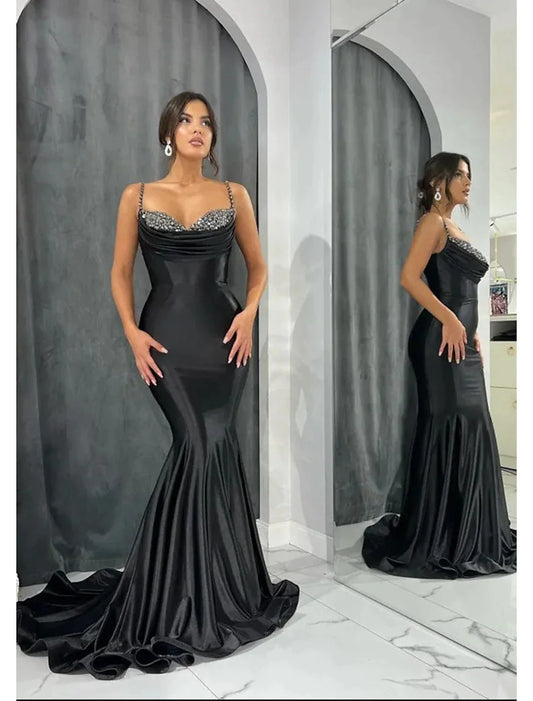 Woman wearing a glamorous sweetheart mermaid trumpet evening gown with an open back and glitter crystals.