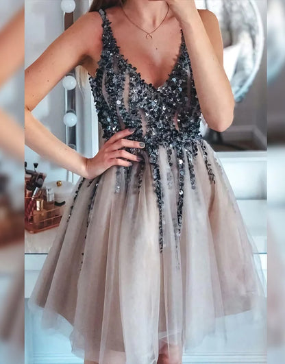 Model wearing a short A-line glitter prom dress with pleating and appliques.