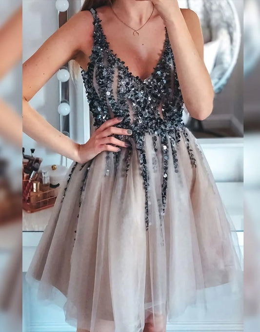 Model wearing a short A-line glitter prom dress with pleating and appliques.