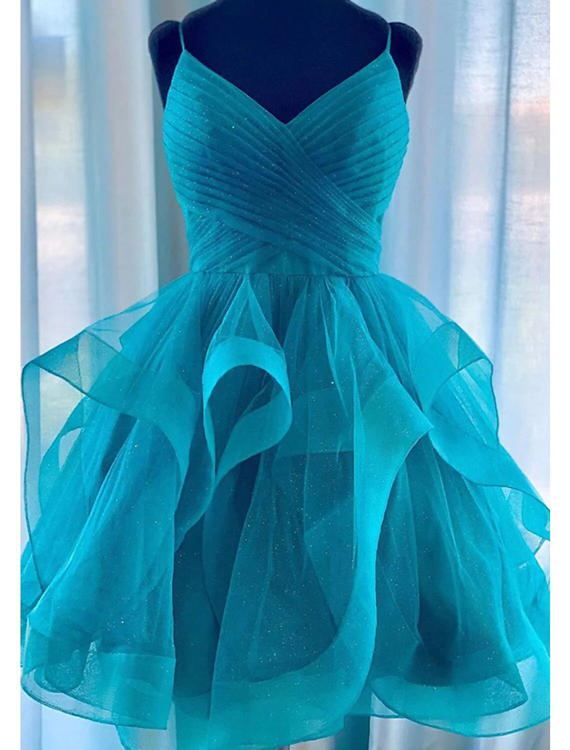 Back view of a woman in a glittery A-line tiered plisse short dress, showcasing ruched details.