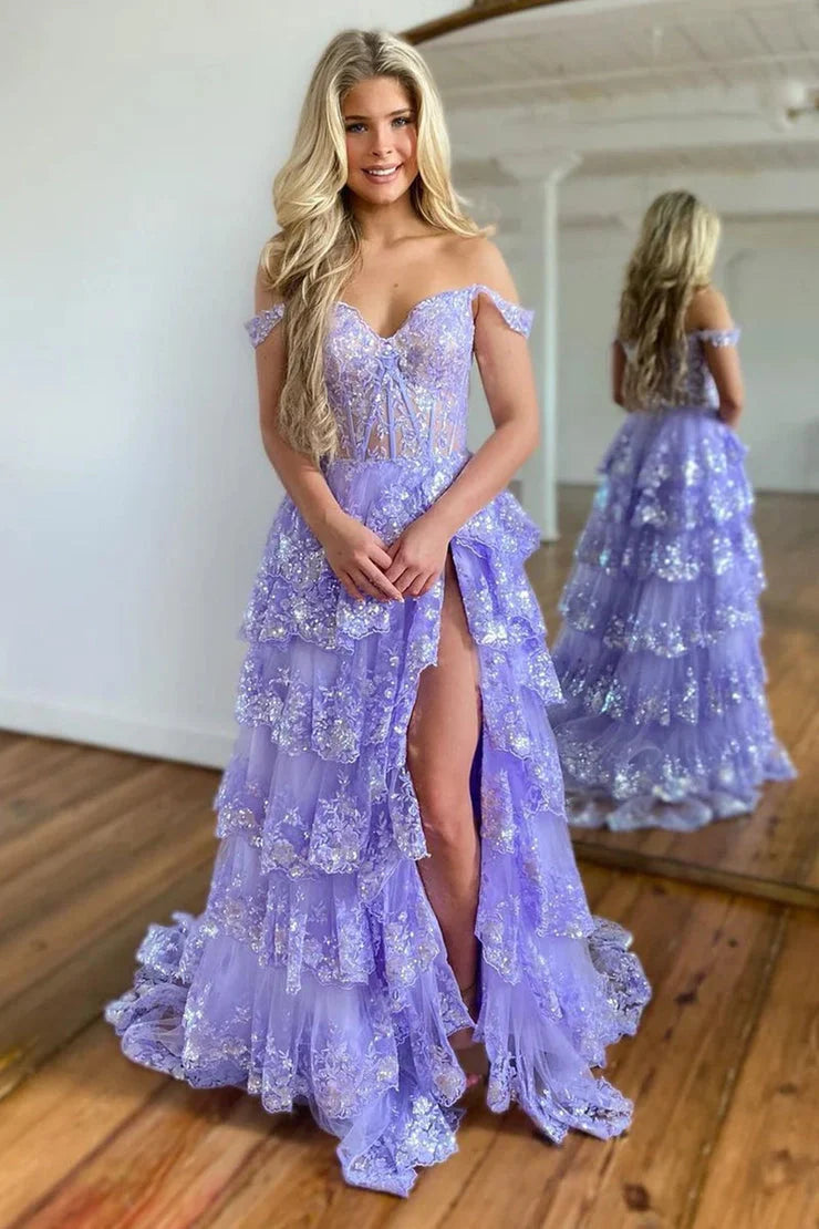Model wearing a light blue off-shoulder tiered ball gown prom dress with a high slit.