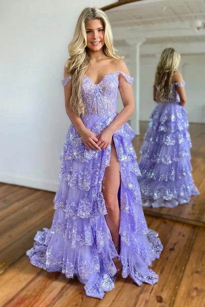 Model wearing a light blue off-shoulder tiered ball gown prom dress with a high slit.