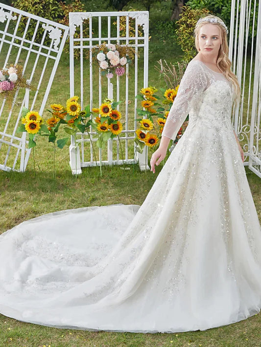 Model wearing a white princess ball gown wedding dress with jewel neck, 3/4 sleeves, and cathedral train.