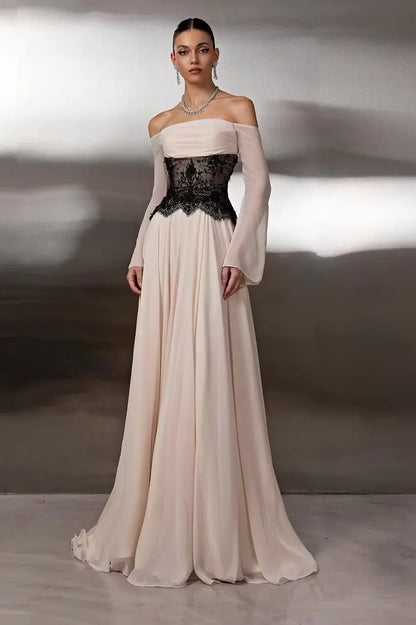 Woman wearing a nude A-line off-shoulder prom dress with black lace corset and sheer long sleeves.