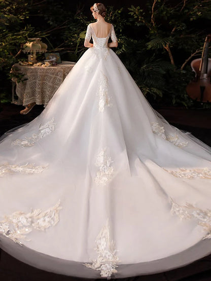 Side view of a white princess ball gown wedding dress, highlighting lace tulle fabric and chapel train.