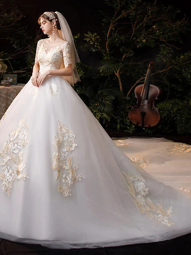 Close-up of the bodice of a white wedding dress, showing jewel neck, short sleeves, and intricate lace appliques.