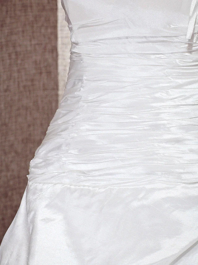 Bride posing in the one-shoulder A-line wedding dress with a sweeping train.