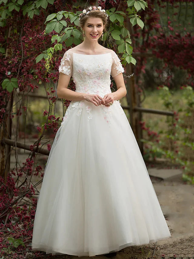 Bride in A-line tulle wedding dress with bateau neck and short sleeves.
