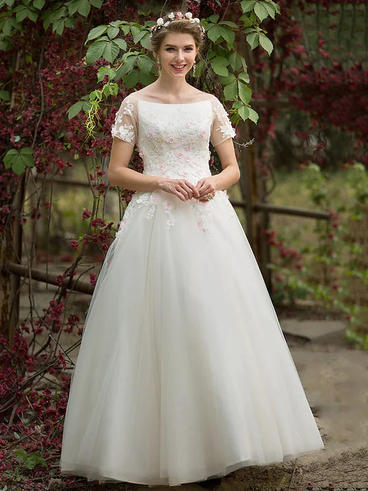 Bride in A-line tulle wedding dress with bateau neck and short sleeves.