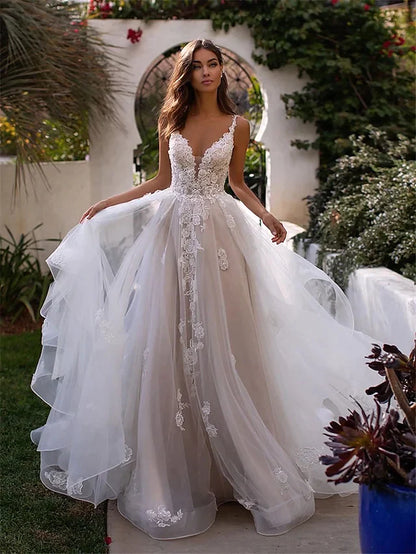 Model wearing A-line V-neck lace wedding dress with spaghetti straps and chapel train.
