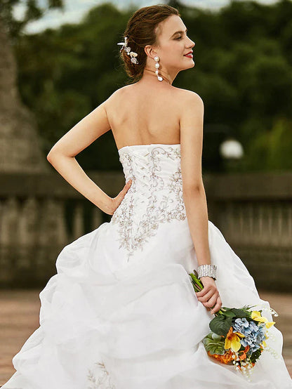 Model wearing a strapless bridal gown, displaying its full silhouette.