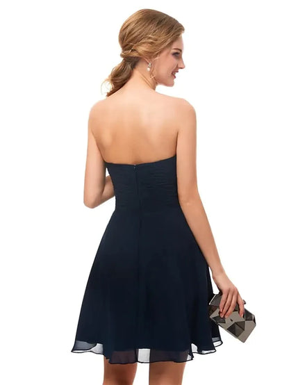 Side view of a model in a black A-line strapless cocktail dress.