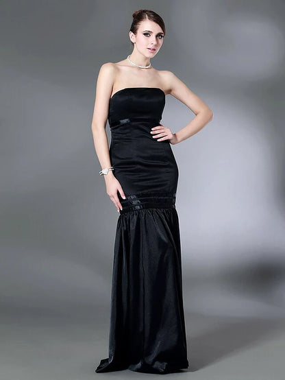 Woman wearing a dark strapless open-back floor-length dress with elegant draping, front view.