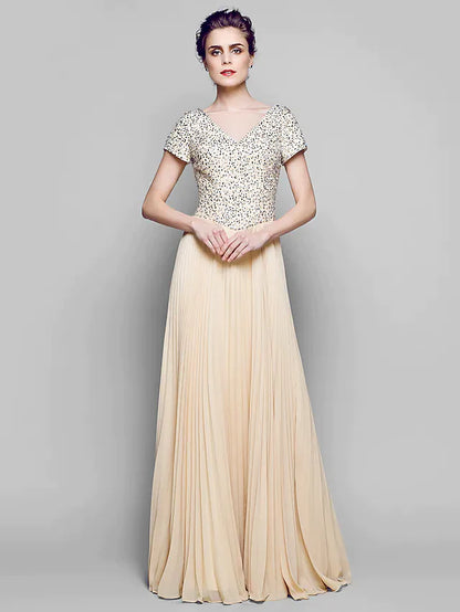 Woman wearing a sparkling A-Line Mother of the Bride gown with a bateau neck and short sleeves.