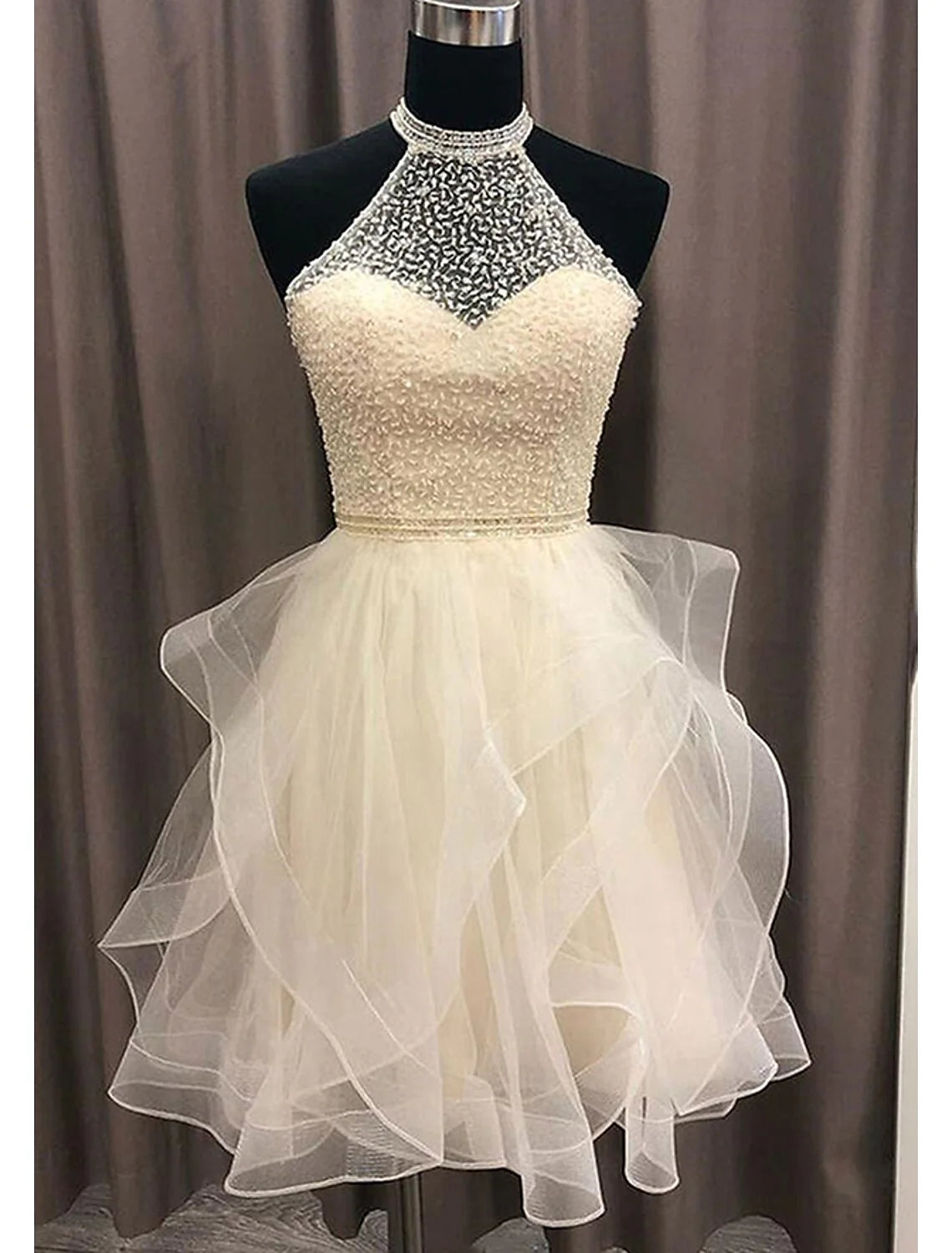 Woman in sparkling A-line halter mini homecoming dress, front view.