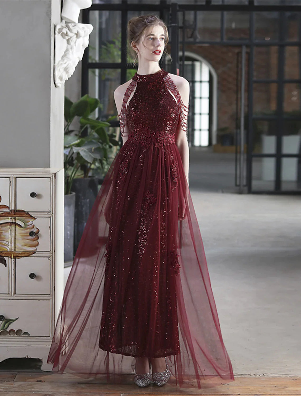 Model posing elegantly in a shimmering A-line floor-length prom gown.