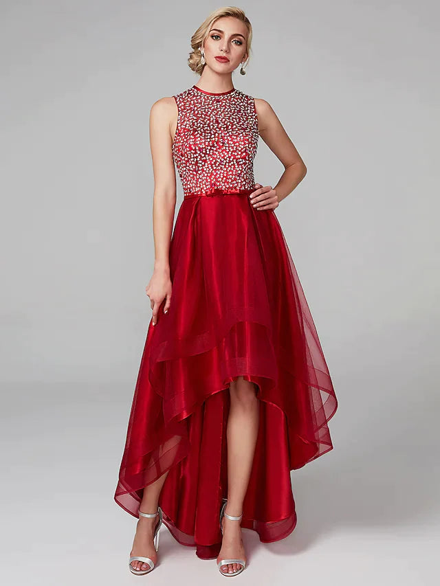 Woman wearing a sparkling A-line high-low cocktail dress with jewel neck and sequin details.