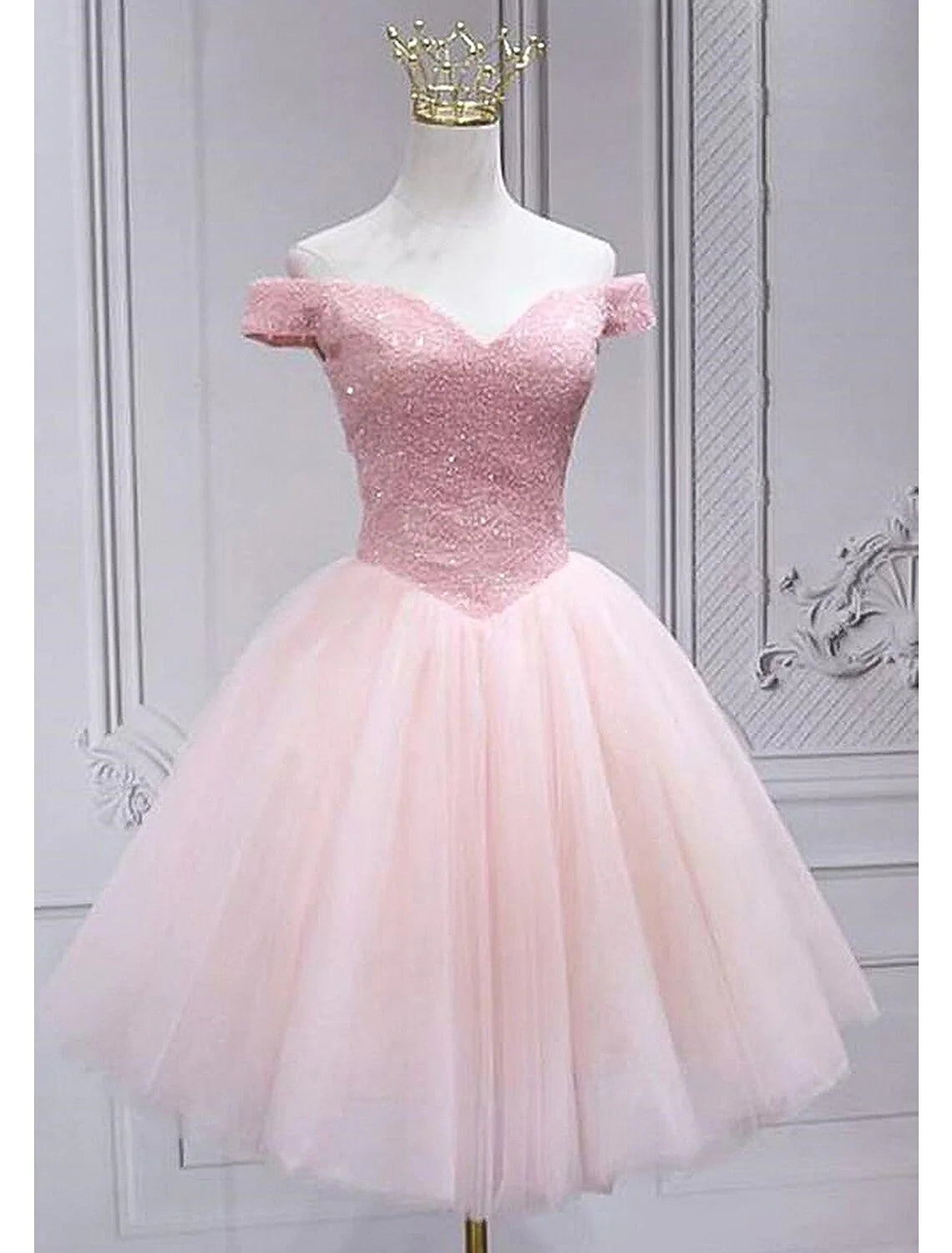 Model wearing a sparkling A-Line off-shoulder knee-length homecoming dress with sequins.