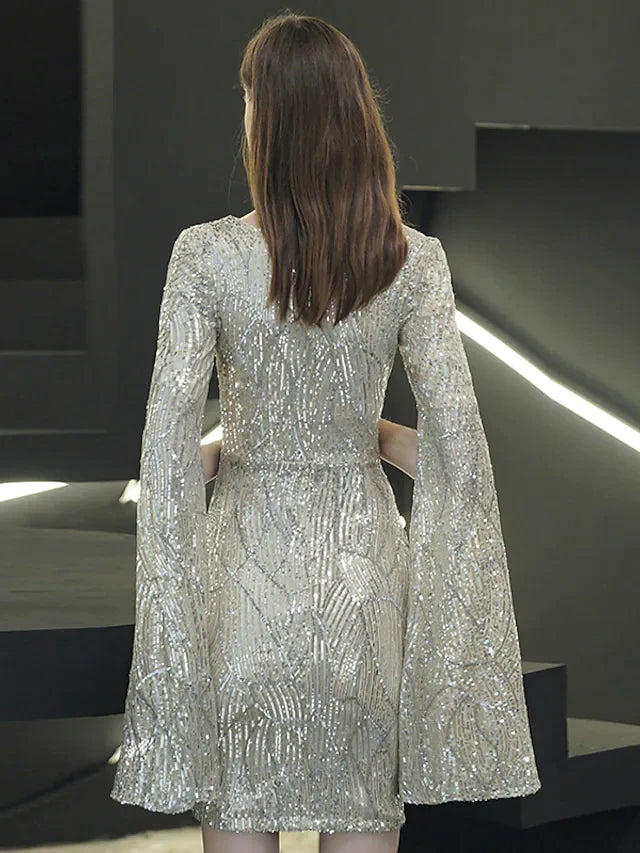 Woman in a sequined mini dress, showing the long sleeves and V-neck.