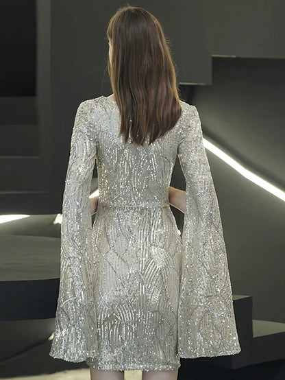 Woman in a sequined mini dress, showing the long sleeves and V-neck.